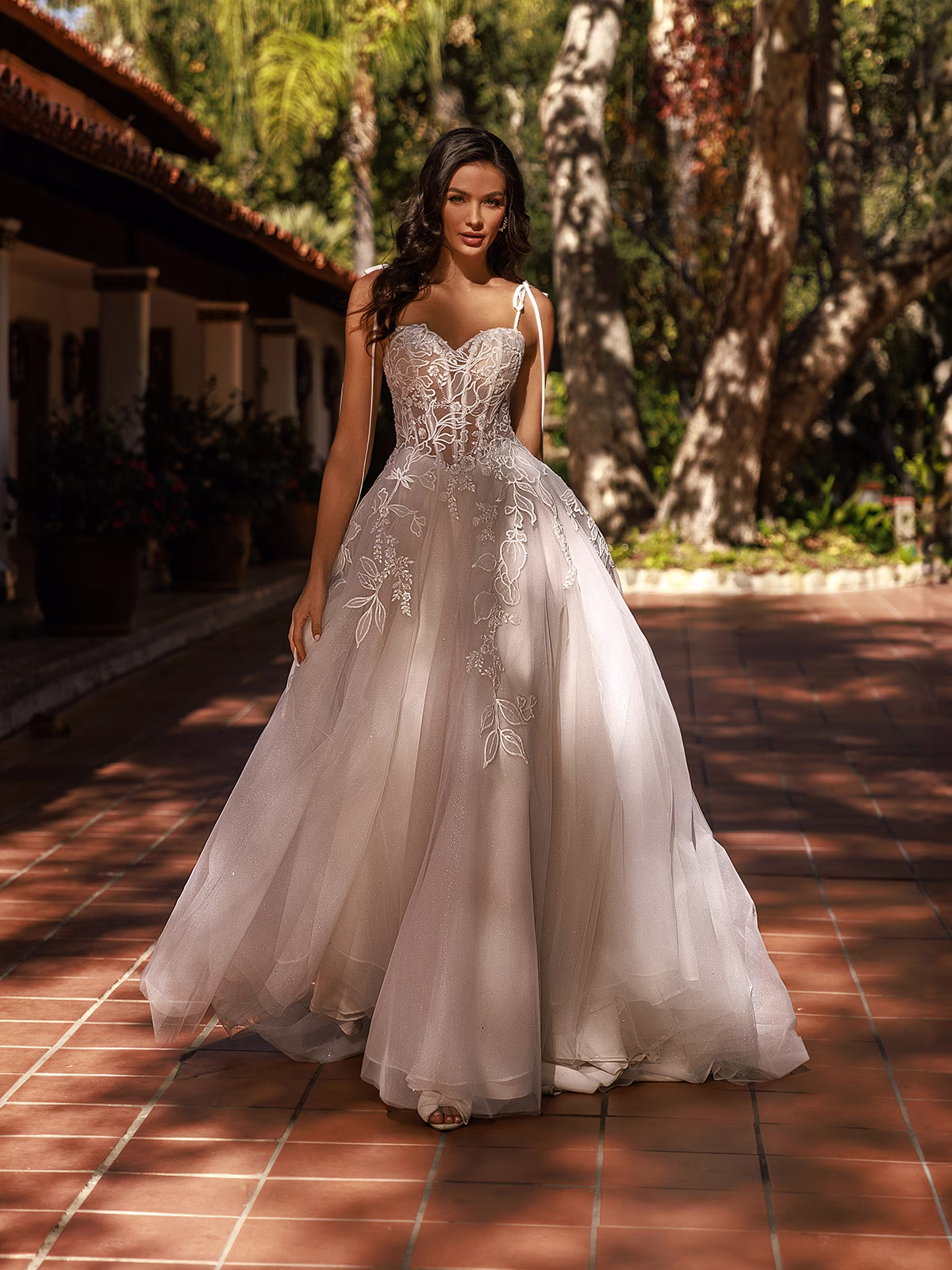 Woman standing outdoors wearing a tulle and sparkle tulle wedding dress with a stunning lace bodice